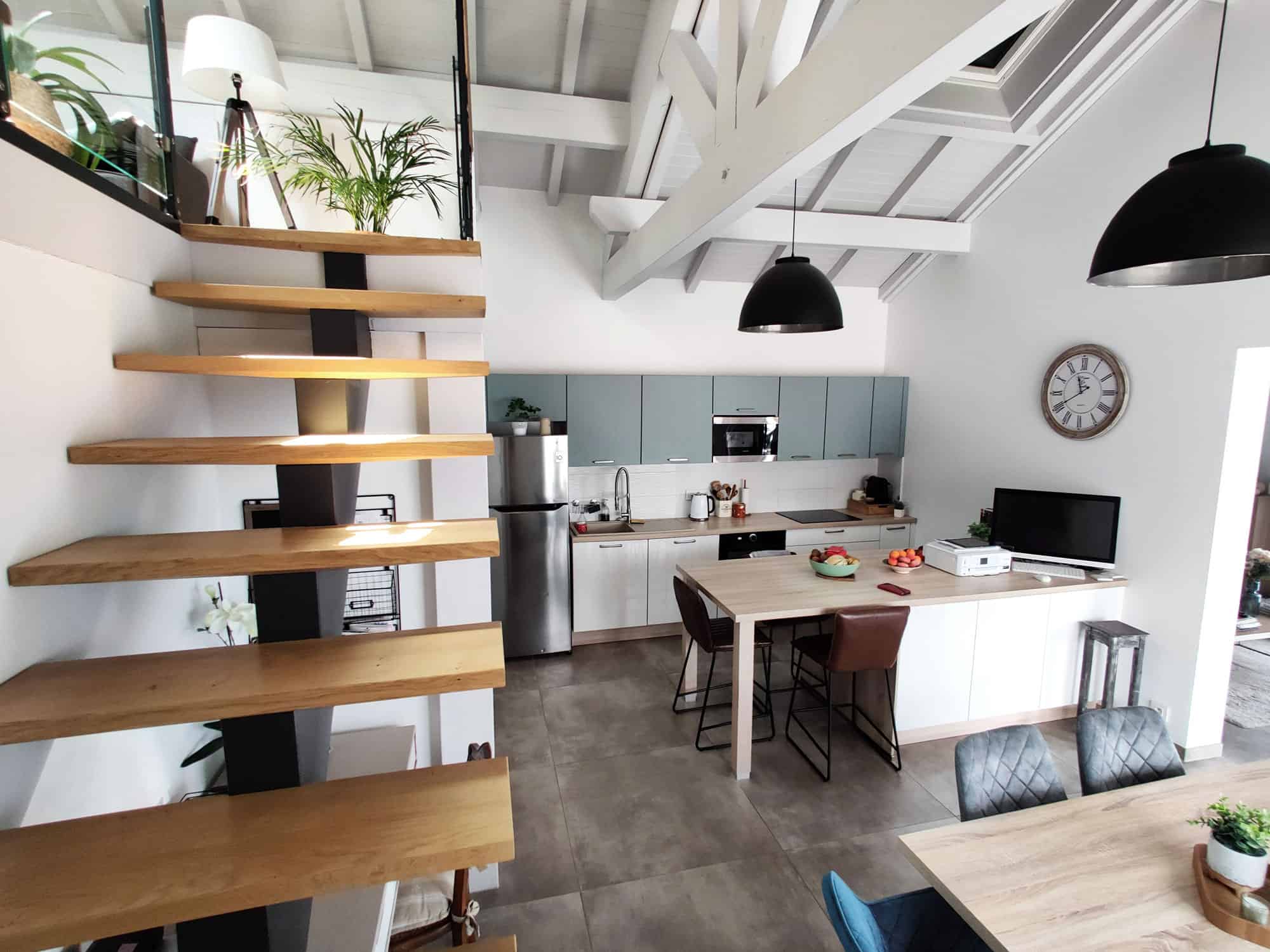 Escalier en bois moderne dans une cuisine lumineuse avec design épuré et structure ouverte.