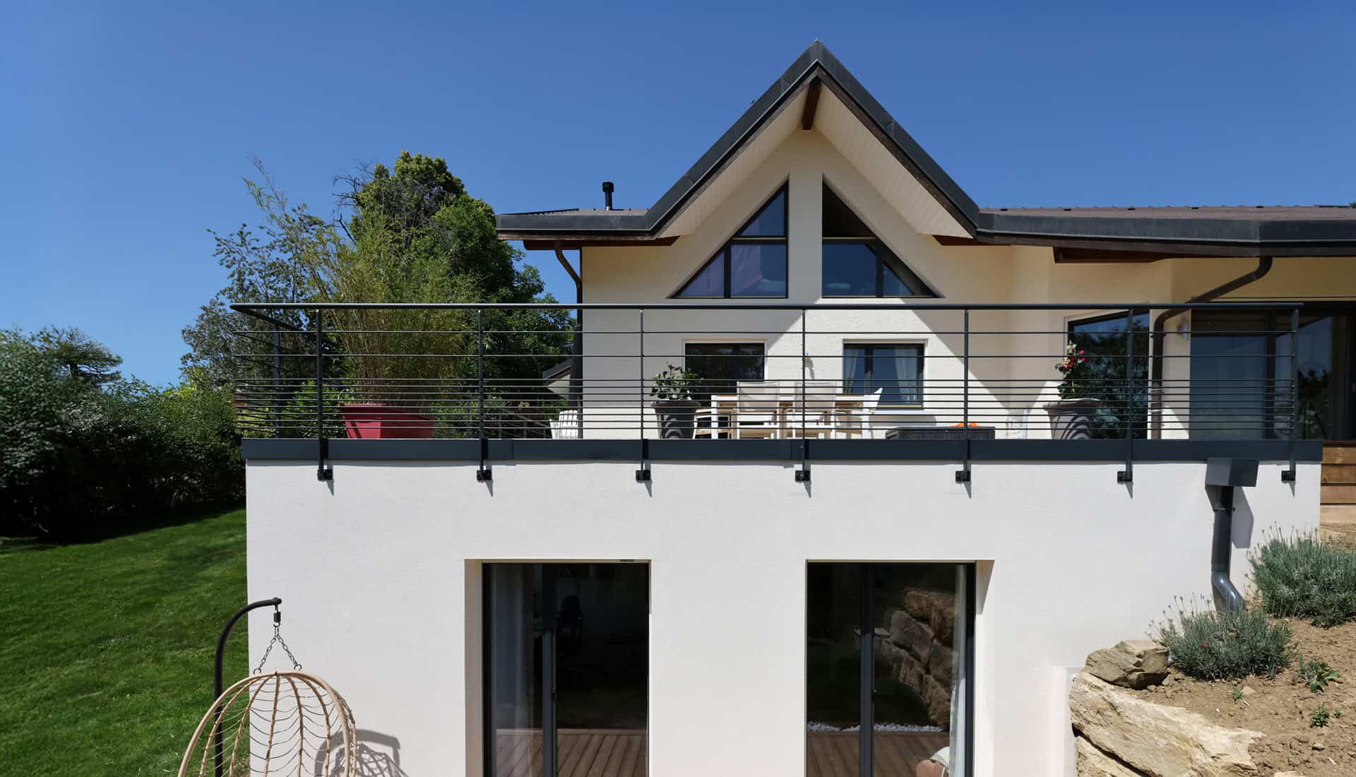 Maison moderne avec terrasse en bois et vue sur le jardin.