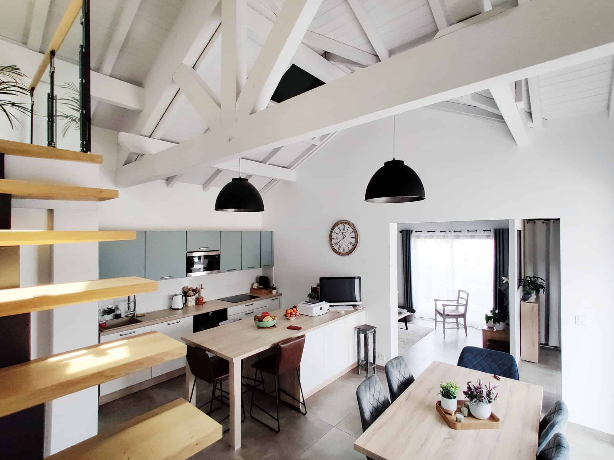 Intérieur lumineux d'un ancien hangar rénové avec cuisine moderne et espace de vie ouvert.