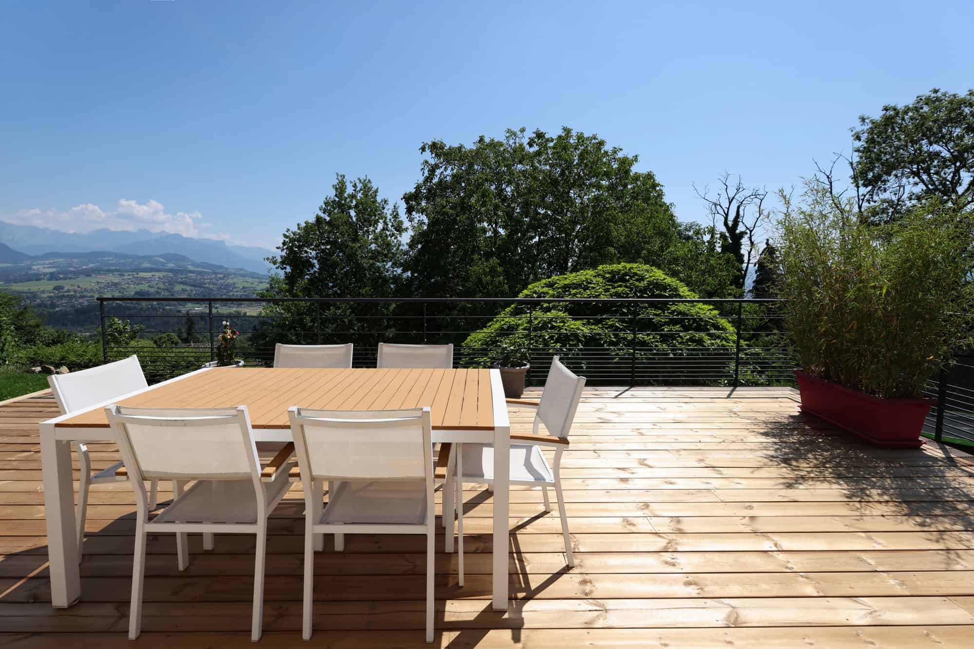 Terrasse en bois avec mobilier moderne et vue dégagée sur la campagne environnante.